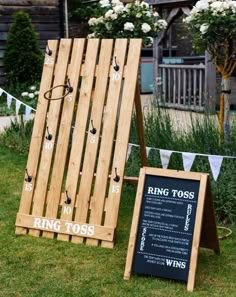 a wooden sign sitting on top of a lush green field next to a chalkboard