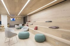 the interior of a modern office with wood paneling and white chairs, blue ottomans and tables