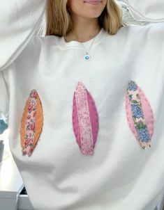 a woman with blonde hair wearing a white sweatshirt with surfboards on it