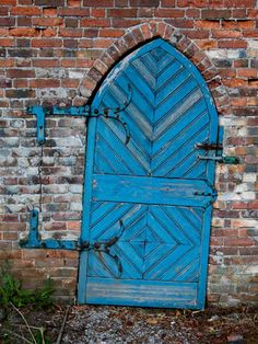 an old blue door in front of a brick wall