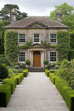 Stone house with climbing ivy and hedged garden path. Explore the quirky charm, secret staircases, and unintentional labyrinths of British country houses, where historical oddities meet modern mishaps in the most delightful way.