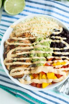 a white bowl filled with chicken, black beans, and guacamole sauce