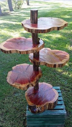 three tiered tree stump stand with red paint on the wood and grass in the background