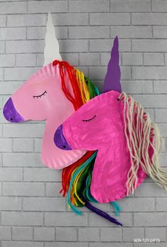 a paper plate unicorn head hanging on a brick wall