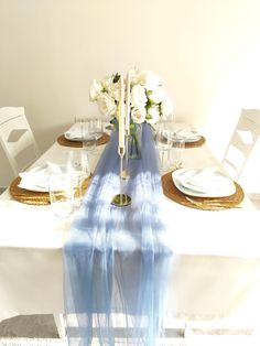 the table is set with white flowers and place settings