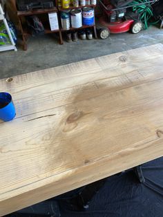 a wooden table with a blue cup sitting on it's top in a garage