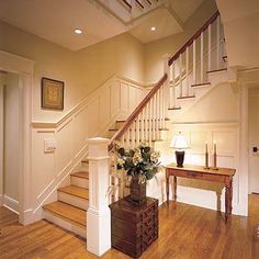 a room with wooden floors and white railings next to a stair case on the wall