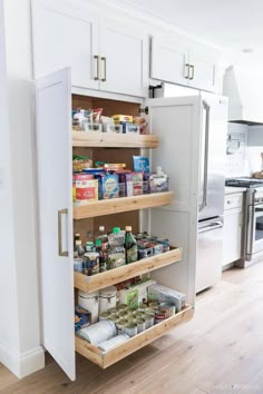 an open pantry door in a kitchen with white cabinets and drawers on the bottom shelf