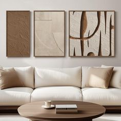 three abstract paintings hang on the wall above a white couch in a modern living room