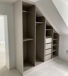 an empty room with some shelves and drawers in the corner on top of the wall