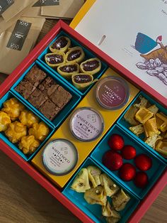 a red box filled with lots of different types of food next to a brown paper bag