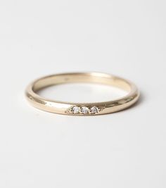 a yellow gold ring with three diamonds on the side, sitting on a white surface