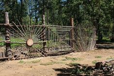 an old iron gate in the middle of a dirt field with trees and bushes behind it