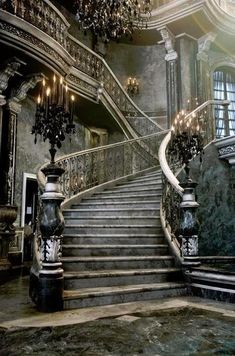 an ornate staircase with chandeliers and lights on the top floor is shown in this image