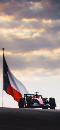 a red white and blue race car with an american flag in the background