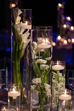 flowers and candles are arranged in glass vases