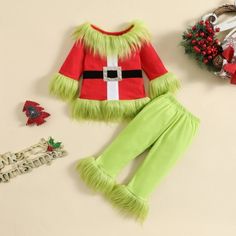 a green and red christmas outfit next to other holiday items on a white table top