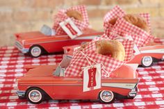 an orange toy car with a donut in the back sitting on a red and white checkered tablecloth