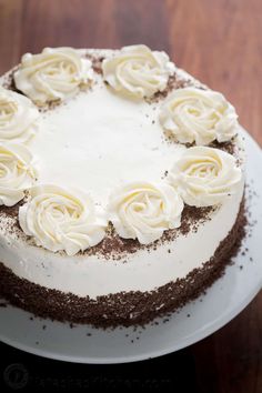 a cake with white frosting and brown sprinkles sitting on a plate