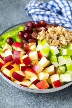 a bowl filled with apples, grapes and walnuts