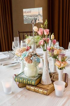 a table topped with books and vases filled with flowers