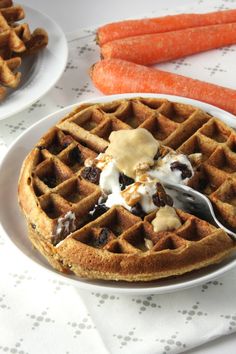 a waffle on a white plate with some carrots next to it and a fork