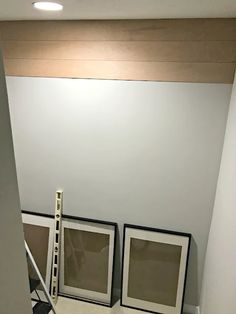 three framed pictures sitting on top of a white floor next to a stair case in a room