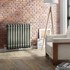 a room with a brick wall and a radiator in the corner, next to a chair