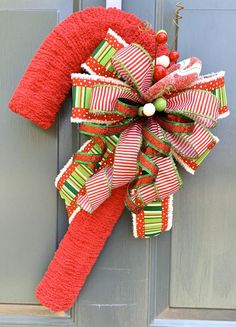 a red and green christmas wreath hanging on the front door with candy canes attached to it