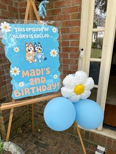 a birthday sign and balloons in front of a brick building with a blue door that says madi's 2nd birthday