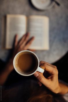 a person holding a cup of coffee with an open book in front of them by jovan for stockstuffs for stockstuffs