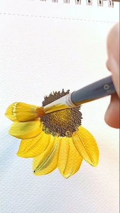 someone is painting a sunflower with watercolors