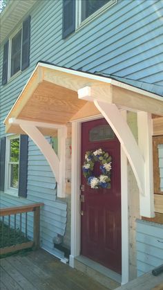 a red front door with a wreath on the top and an awning over it