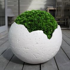 a white planter sitting on top of a wooden table next to a patio area