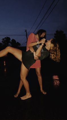 two women are dancing in the rain at night with their feet on each other's shoulders