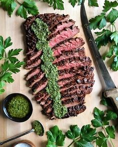 the steak is prepared and ready to be cut into pieces with green sauce on it