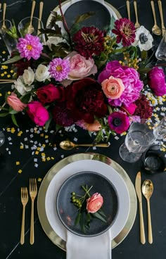 the table is set with flowers and gold cutlery, plates and utensils