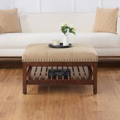 a living room with a couch, coffee table and vase on top of the ottoman