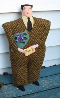 a doll is sitting on a bench wearing a suit and tie with flowers in his pocket