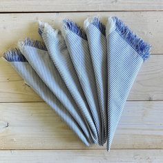 six blue and white striped napkins folded on top of each other with fray edges