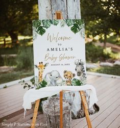 a welcome sign for a baby shower is displayed on a wooden easel with an elephant and giraffe theme