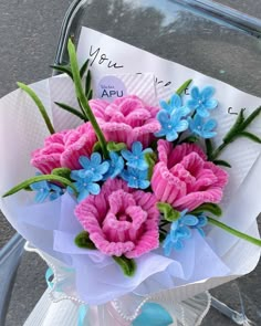 a bouquet of pink and blue flowers sitting on top of a white paper wrapper