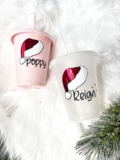 two plastic cups with the words happy and reign on them sitting next to a pine tree