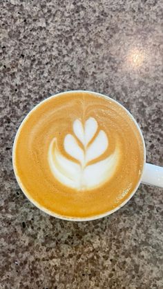 a cappuccino with a leaf design in it on a marble counter top