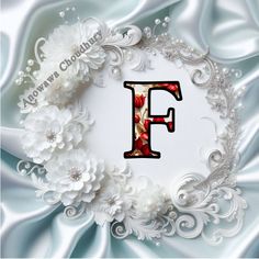 the letter f is surrounded by white flowers and pearls on a blue satin fabric background