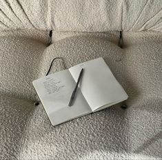 an open notebook with a pen on top of it sitting on a bed sheet that is covered in white sheets