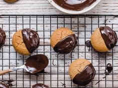 chocolate frosted cookies on a cooling rack with one cookie being drizzled