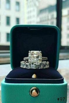 an engagement ring in a green box on top of a marble table with buildings in the background