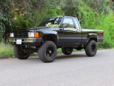 a black pick up truck parked on the side of a road in front of trees