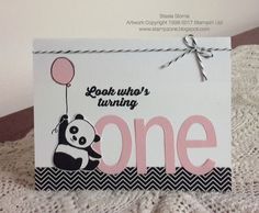 a panda bear holding a pink balloon on top of a white sign that says look where's turning one